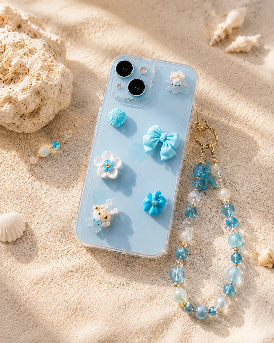 Blaue Charmhülle mit Kette und Perlen am Strand